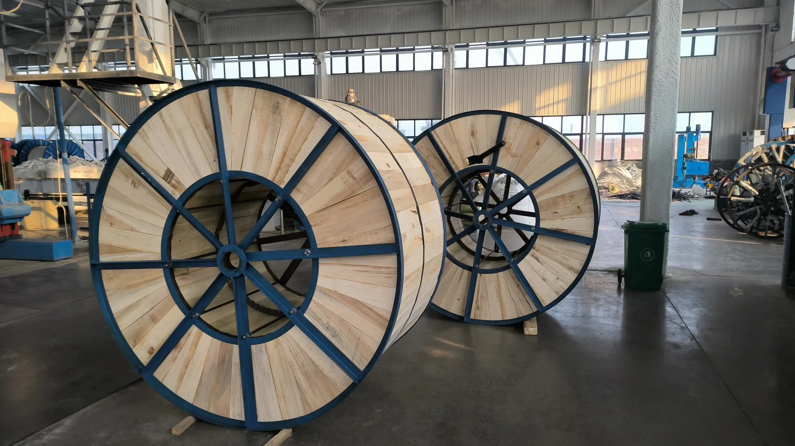 Rows of empty wooden and steel-flanged cable drums stacked in the open yard of our cable factory before being loaded with finished cable
