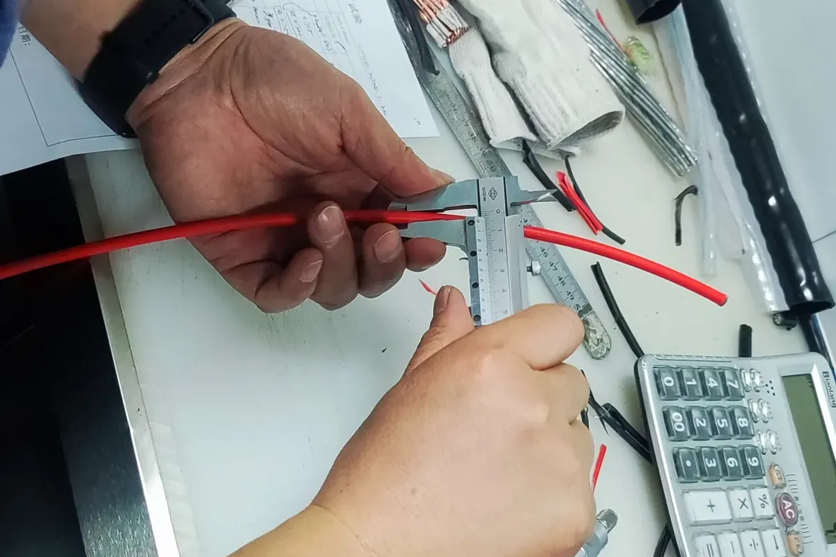 Operator measuring insulation thickness and cable diameter on a projection measuring instrument in the factory test laboratory